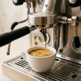 Espresso pouring into a white ceramic cup with golden crema.